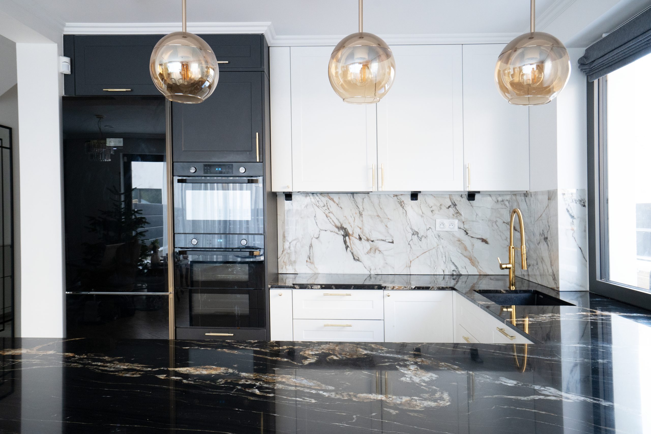 A modern kitchen with marble countertops and pendant lights